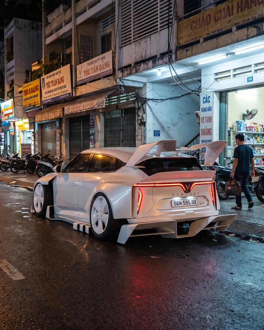 Rear of the white VF7 Widebody on a Saigon street with its swan-neck wings, AI render