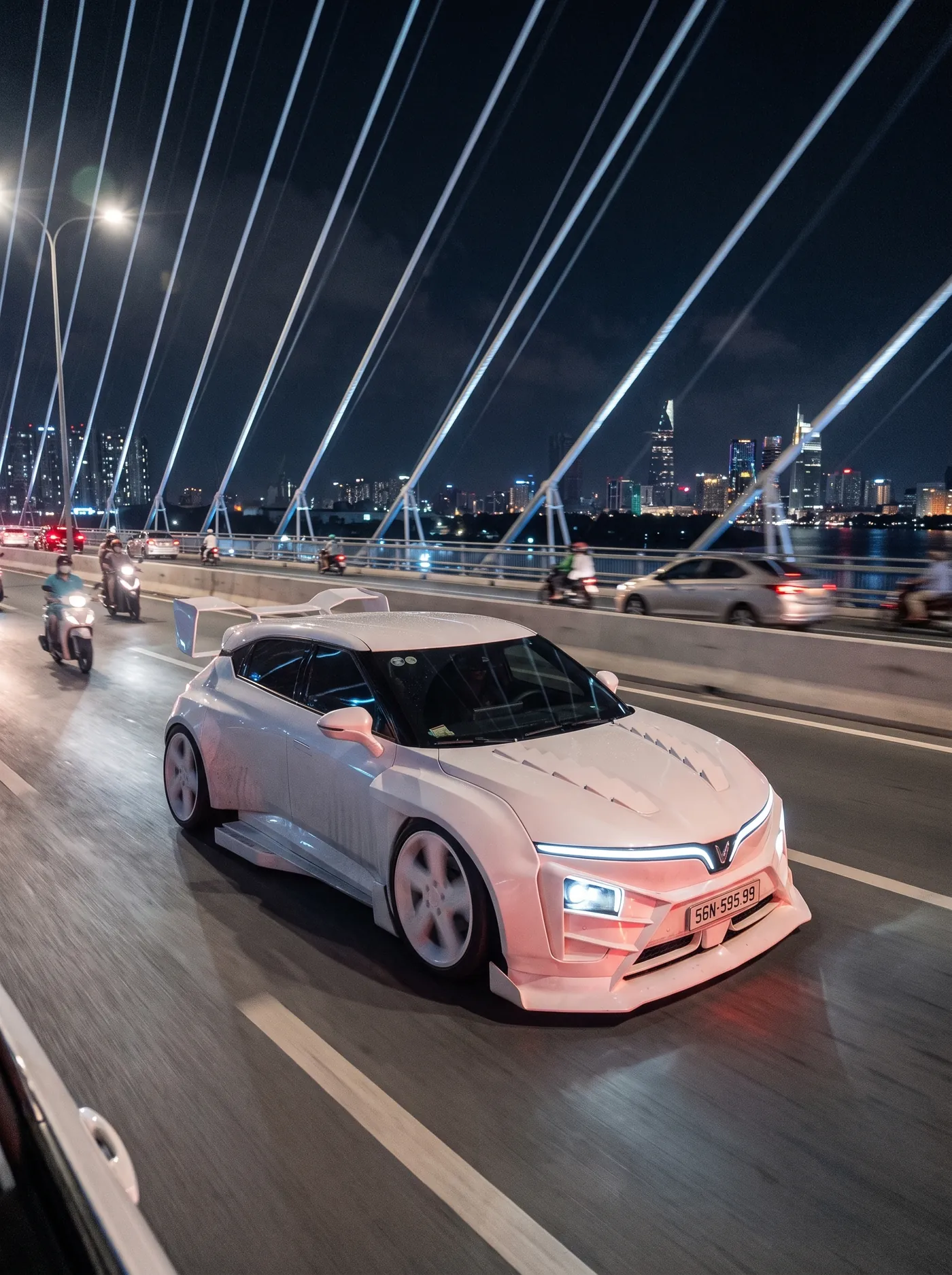 White VF7 Widebody crossing a cable-stayed bridge in Saigon at night, AI render